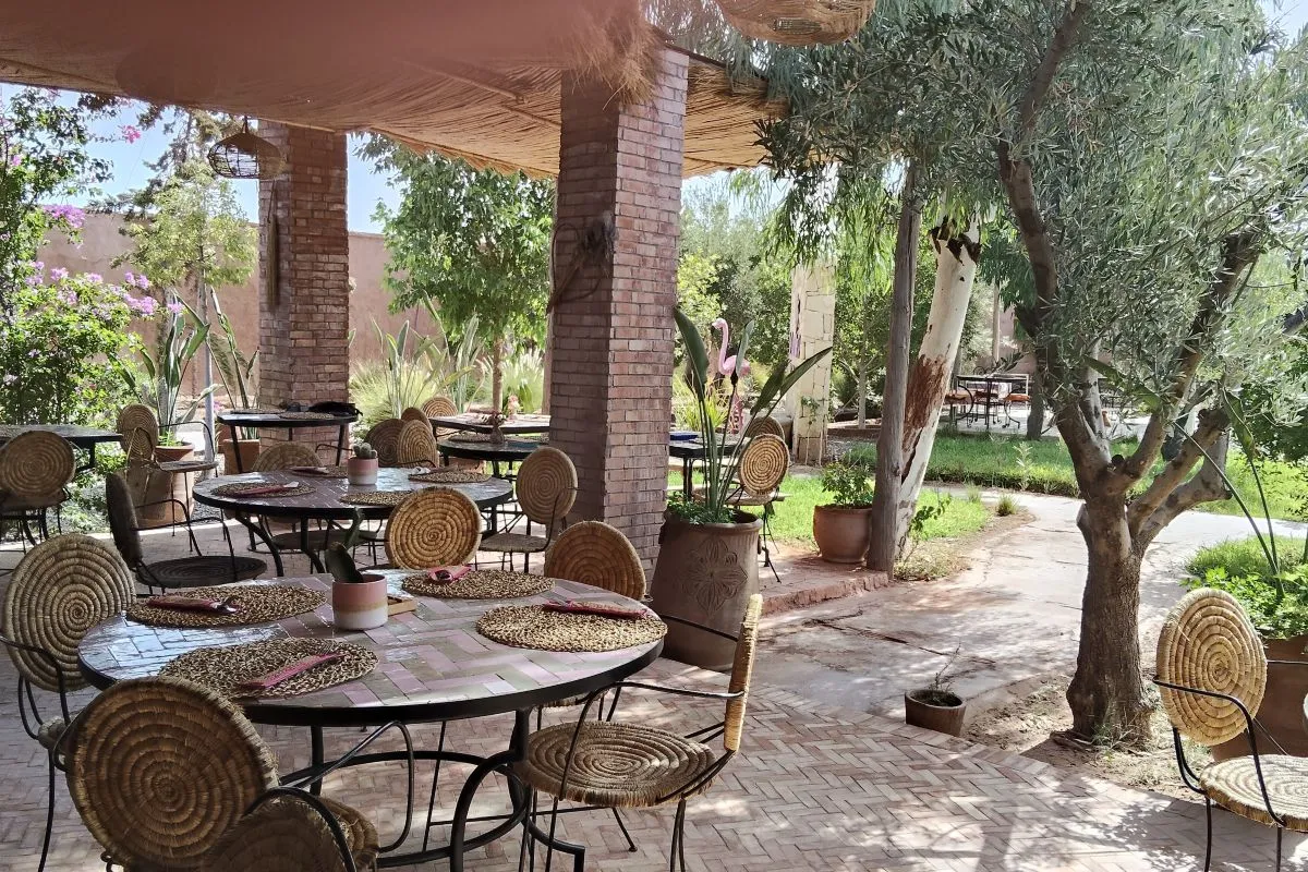 Salle de restaurant extérieure ombragée avec tables rondes en mosaïque à La Secret Beach Marrakech — La Secret Beach, beach club 100 % femmes à Marrakech
